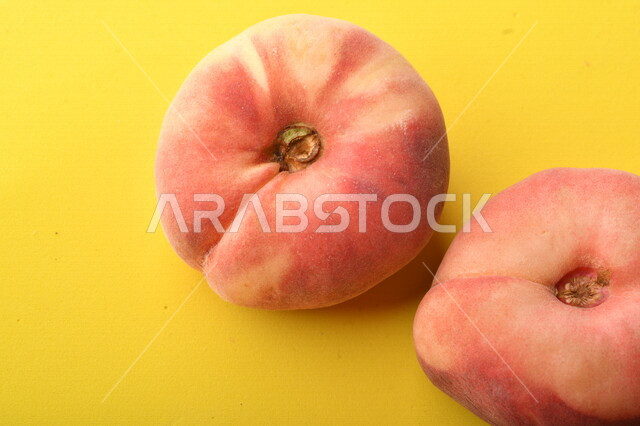 صورة لفاكهة الخوخ المسطح اللذيذ على خلفية صفراء ، ثمرة الدّراق الصحية اللذيذة ، فاكهة الدُّراق المُبلَّط وتسمى كعب الغزال ، فاكهة صيفية