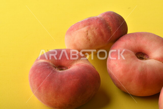 صورة لفاكهة الخوخ المسطح اللذيذ على خلفية صفراء ، ثمرة الدّراق الصحية اللذيذة ، فاكهة الدُّراق المُبلَّط وتسمى كعب الغزال ، فاكهة صيفية