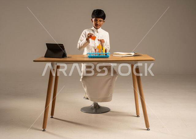 Effective learning methods using technology and technological devices, using experimental educational tools and means, portrait of a Saudi Arabian Gulf student wearing school uniform and safety glasses sitting behind an examination table and sample tubes and chemical analyses, gray background