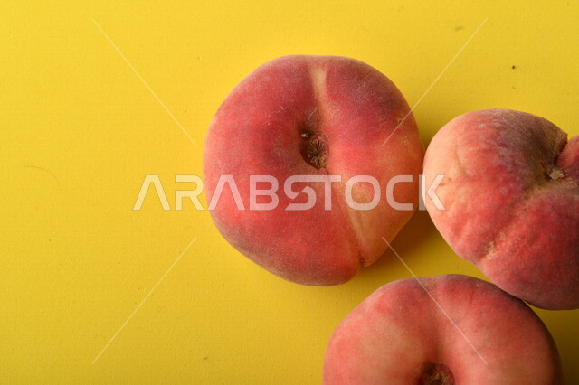 صورة لفاكهة الخوخ المسطح اللذيذ على خلفية صفراء ، ثمرة الدّراق الصحية اللذيذة ، فاكهة الدُّراق المُبلَّط وتسمى كعب الغزال ، فاكهة صيفية