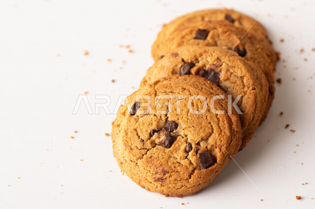 رقائق الشوكولاته الساخنه على خلفية بيضاء ، رقاقات البسكويت الهشة والخفيفة مع قطع الشوكولاته الداكنة اللذيذة ، كوكيز ، بسكويت برقائق الشوكولاتة ، حلويات مخبوزة طازجة