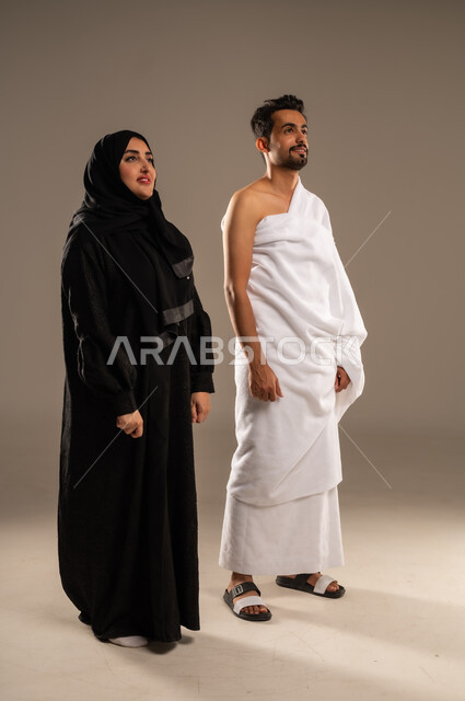 ايماءات السعادة والطمأنينة، زيارة بيت الله الحرام في مكه المكرمة، بورتريه مقرب لزوجان عربيان خليحيان سعوديان يرتديان ثياب الإحرام بإستعداد لأداء مناسك فريضة الحج والعمره، التقرب الى الله بالأعمال الصالحة، تلبية الركن الخامس من أركان الإسلام، الجسم بالطول الكامل، خلفية بيج