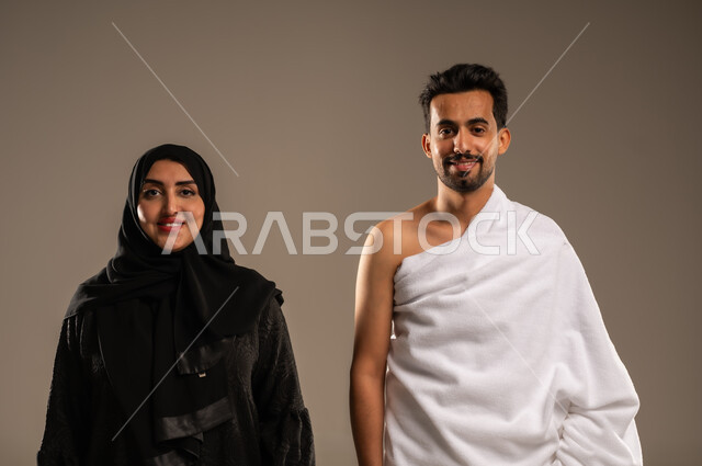 ايماءات السعادة والطمأنينة، زيارة بيت الله الحرام في مكه المكرمة، بورتريه مقرب لزوجان عربيان خليحيان سعوديان يرتديان ثياب الإحرام بإستعداد لأداء مناسك الحج والعمره، مفهوم الألفة بين الزوجين، التقرب الى الله بالأعمال الصالحة، تلبية الركن الخامس من أركان الإسلام، خلفية بيج