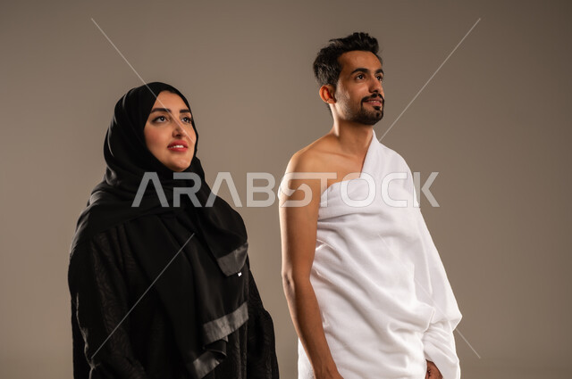 ايماءات السعادة والطمأنينة، زيارة بيت الله الحرام في مكه المكرمة، بورتريه مقرب لزوجان عربيان خليحيان سعوديان يرتديان ثياب الإحرام بإستعداد لأداء مناسك الحج والعمره، مفهوم الألفة بين الزوجين، التقرب الى الله بالأعمال الصالحة، تلبية الركن الخامس من أركان الإسلام، خلفية بيج