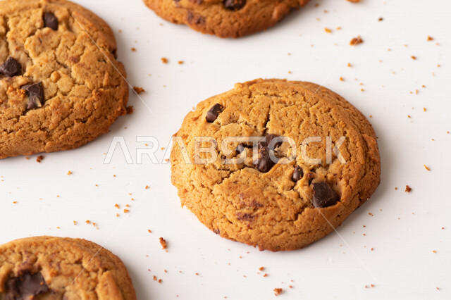 رقائق الشوكولاته الساخنه على خلفية بيضاء ، رقاقات البسكويت الهشة والخفيفة مع قطع الشوكولاته الداكنة اللذيذة ، كوكيز ، بسكويت برقائق الشوكولاتة ، حلويات مخبوزة طازجة