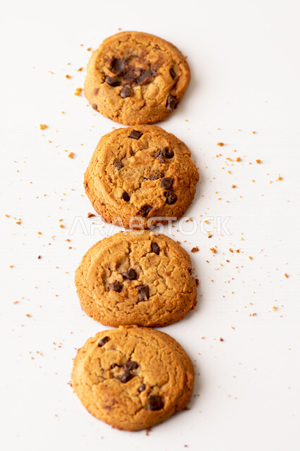 رقائق الشوكولاته الساخنه على خلفية بيضاء ، رقاقات البسكويت الهشة والخفيفة مع قطع الشوكولاته الداكنة اللذيذة ، كوكيز ، بسكويت برقائق الشوكولاتة ، حلويات مخبوزة طازجة