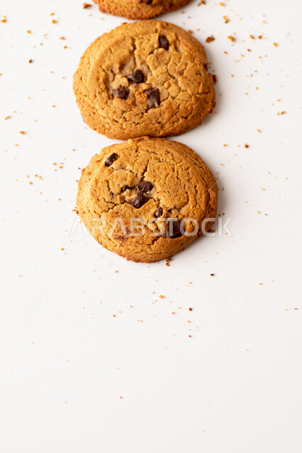 رقائق الشوكولاته الساخنه على خلفية بيضاء ، رقاقات البسكويت الهشة والخفيفة مع قطع الشوكولاته الداكنة اللذيذة ، كوكيز ، بسكويت برقائق الشوكولاتة ، حلويات مخبوزة طازجة