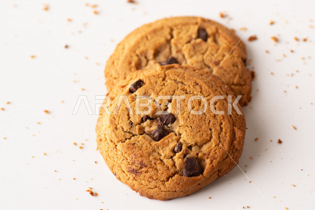 رقائق الشوكولاته الساخنه على خلفية بيضاء ، رقاقات البسكويت الهشة والخفيفة مع قطع الشوكولاته الداكنة اللذيذة ، كوكيز ، بسكويت برقائق الشوكولاتة ، حلويات مخبوزة طازجة