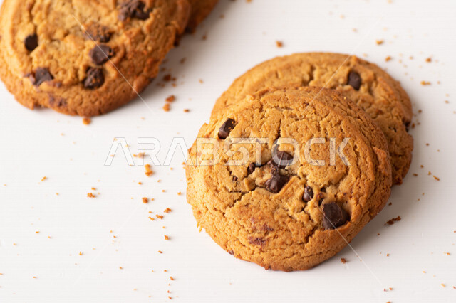 رقائق الشوكولاته الساخنه على خلفية بيضاء ، رقاقات البسكويت الهشة والخفيفة مع قطع الشوكولاته الداكنة اللذيذة ، كوكيز ، بسكويت برقائق الشوكولاتة ، حلويات مخبوزة طازجة