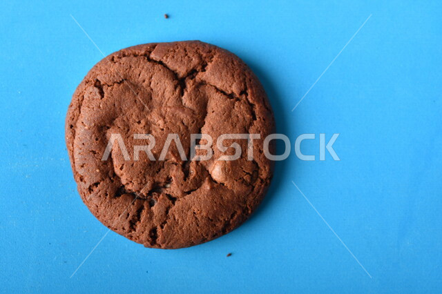 صورة لرقائق الشوكولاته الساخنه على خلفية زرقاء ، رقاقات البسكويت الهشة والخفيفة مع قطع الشوكولاته الداكنة اللذيذة ، كوكيز ، بسكويت برقائق الشوكولاتة ، حلويات مخبوزة طازجة