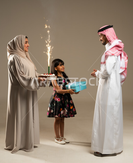 الألفة والمودة بين أفراد الأسرة السعودية, ايماءات البهجة والسرور, الاجتماعات والاحتفالات العائلية، بورتريه لعائلة عربية خليجية سعودية يحتفلون بعيد ميلاد الأب ويقدمون له قالب الكيك المزين والهدايا، خلفية بيج