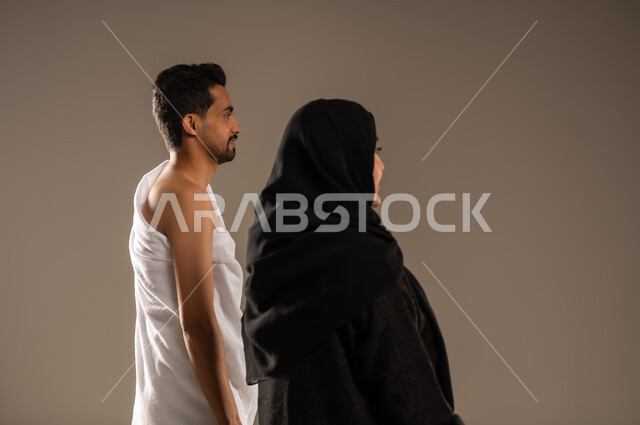 زيارة بيت الله الحرام في مكه المكرمه، مفهوم الألفة بين الزوجين, بورتريه مقرب من الخلف لزوجان عربيان خليحيان سعوديان يرتديان ثياب الإحرام بإستعداد لأداء مناسك فريضة الحج والعمره، التقرب الى الله بالأعمال الصالحة، تلبية الركن الخامس من أركان الإسلام, خلفية بيج