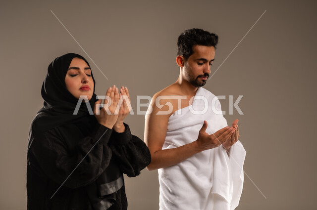 أداء مناسك الحج والعمرة، المحافظة على الصلوات والدعاء وطلب المغفرة من الله تعالى، بورتريه مقرب لزوجين عربيين خليجيين سعوديين يرتديان ثياب الإحرام يدعوان بخشوع وتضرع، الركن الخامس من أركان الإسلام، خلفية بيج