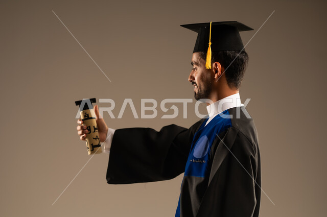 Gestures of pride and happiness, close-up side portrait of a Saudi Arabian Gulf student wearing an abaya and graduation cap holding a certificate of excellence and success in his hand and looking at it, celebrating the completion of university studies, brown background