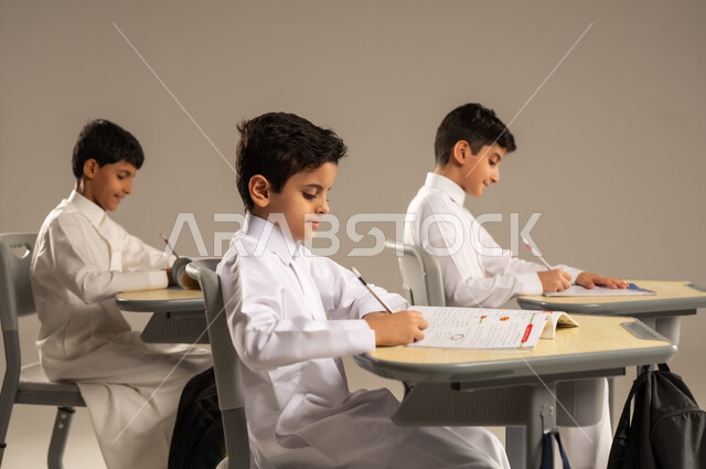 المشاركة والتعاون بين الزملاء، جودة أساليب التعلم الفعال، موسم العودة إلى المدارس، بورتريه لطلاب عربيين خليجيين سعوديين يرتدون الزي المدرسي يجلسون في مقاعدهم وأمامهم الكتب والمقررات المدرسية، أهداف التربية والتعليم في المملكة العربية السعودية، خلفية بيج