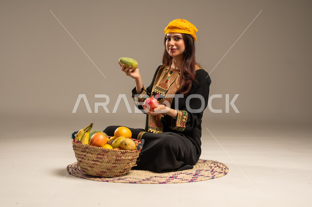Local agricultural crops and products, the anniversary of the founding of the first Saudi state, February 22, national holidays and occasions, a portrait of a young Saudi Gulf Arab woman wearing a shayla and a sidr tree sitting on a straw mat looking at the camera holding fresh fruits in her hand, the day we began 1727 AD, beige background