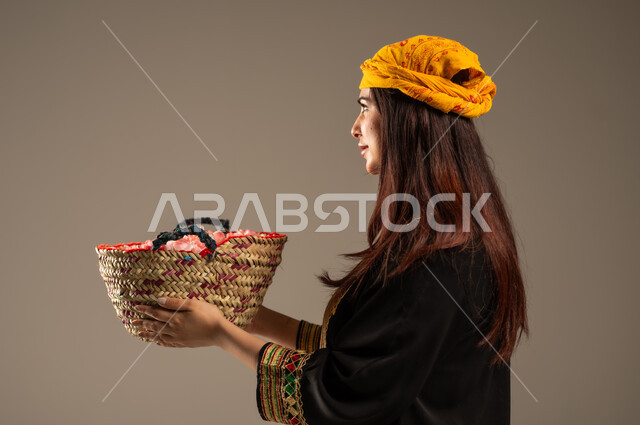 ذكرى تأسيس الدولة السعودية الاولى 22 فبراير، المناسبات والأعياد الوطنية، بورتريه مقرب من الجانب لشابة عربية خليجية سعودية ترتدي الشيلة والسدرة تحمل بيدها سلة من القش ممتلئة بالورد الجوري الطبيعي، يوم بدينا 1727 م، مفهوم حب الوطن والانتماء اليه، خلفية بيج