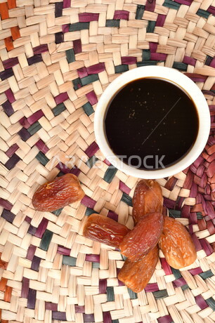 صورة لمجموعة من حبات التمر بجانب وعاء دبس التمر الصحي ، وعاء من القش ، عسل التمر ، غذاء صحي ولذيذ