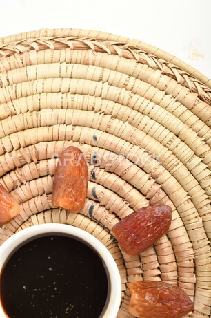 صورة لمجموعة من حبات التمر بجانب وعاء دبس التمر الصحي ، وعاء من القش ، عسل التمر ، غذاء صحي ولذيذ