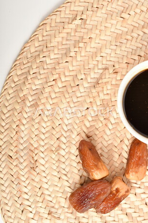 A picture of a bunch of dates next to a bowl of healthy date molasses, a bowl of straw, date honey, healthy and delicious food