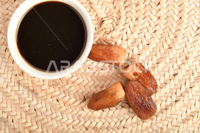 صورة لمجموعة من حبات التمر بجانب وعاء دبس التمر الصحي ، وعاء من القش ، عسل التمر ، غذاء صحي ولذيذ