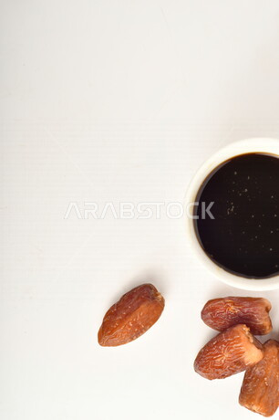 مجموعة من حبات التمر بجانب وعاء دبس التمر الصحي ، خلفية بيضاء ، عسل التمر ، غذاء صحي ولذيذ