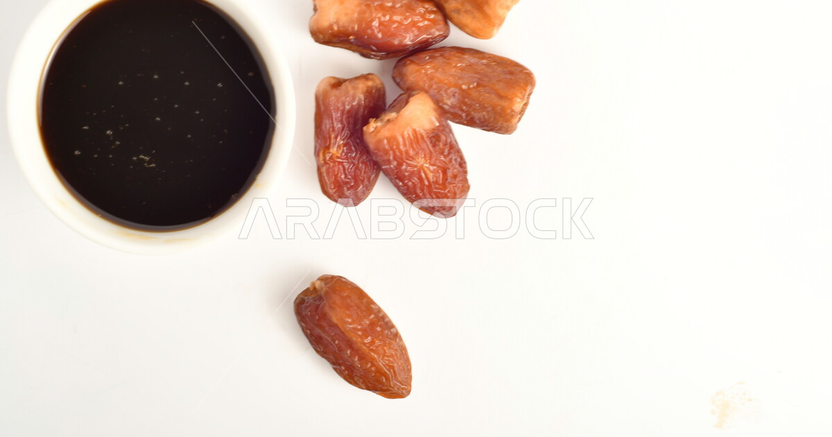 A group of date kernels beside a bowl of healthy date molasses ...