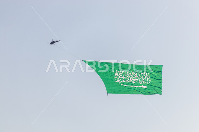 طائرة هليكوبتر تحمل العلم تحلق في السماء، الاحتفال بالمناسبات والأعياد الوطنية، ذكرى اليوم الوطني 23 سبتمبر، راية التوحيد والإسلام وشعار الهوية الوطنية، خلفية السماء الزرقاء