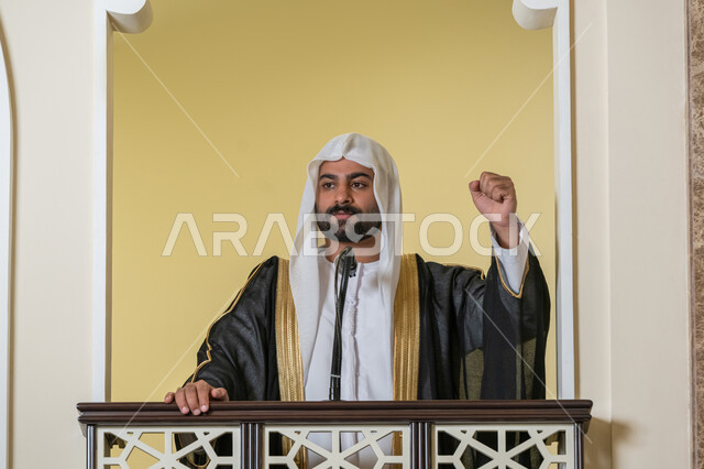 توجيه الناس نحو الحق والهداية, مفهوم العبادة والتقرب إلى الله تعالى, تعزيز الروحانية الجماعية, دور أئمة المساجد والخطباء في نشر الدين، إمام عربي خليجي إماراتي يرتدي البشت والكندورة والغترة البيضاء يقف أمام مكبر الصوت ويلقي الخطبة على المنبر