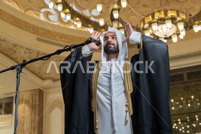 الشعور بالخشوع والطمأنينة, الركن الثاني من أركان الإسلام, أداء فرائض الدين الإسلامي, إمامة المسلمين في المسجد, إقامة الصلاة على وقتها، صورة مقربة لإمام عربي خليجي إماراتي يرتدي البشت والكندورة والغترة البيضاء يقوم بأداء فريضة الصلاة ويرفع يديه لتكبيرة الإحرام