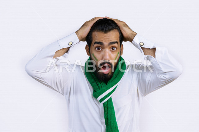 بورتريه لشاب عربي سعودي خليجي يضع وشاح نادي الفريق  ، مشجع لفريق الأهلي وفريق السعودية ، ايماءات وجه ويدين تدل على الصدمة و الذهول , أندية وتشجيع , خلفية بيضاء .