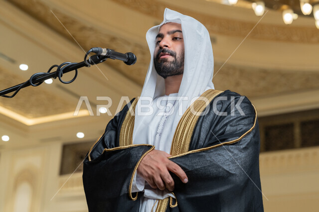 إقامة الصلاة على وقتها، إمامة المسلمين في المسجد, الشعور بالخشوع والطمأنينة, الركن الثاني من أركان الإسلام, أداء فرائض الدين الإسلامي, صورة مقربة لإمام عربي خليجي إماراتي يرتدي البشت والكندورة والغترة البيضاء يقوم بأداء فريضة الصلاة