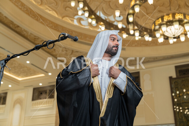 الاستعداد لاقامة الصلاة على وقتها، إمامة المسلمين في المسجد, الشعور بالخشوع والطمأنينة, الركن الثاني من أركان الإسلام, أداء فرائض الدين الإسلامي, صورة مقربة لإمام عربي خليجي إماراتي يرتدي البشت والكندورة والغترة البيضاء يقوم بأداء فريضة الصلاة