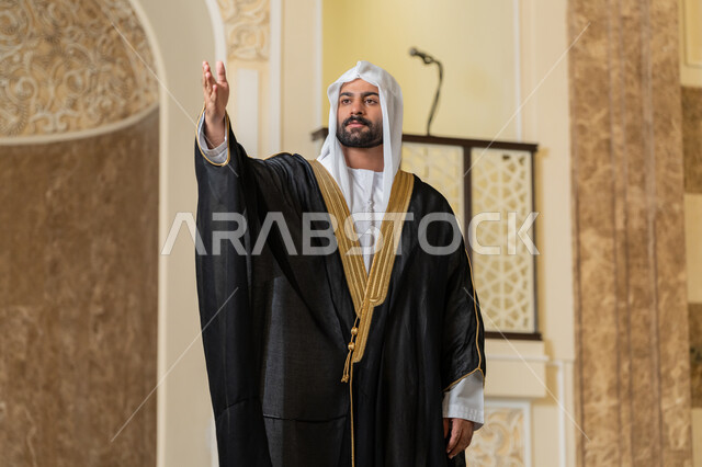 إلقاء التحيه والسلام, مفهوم الاستقبال والترحيب، صورة لرجل عربي خليجي إماراتي يرتدي البشت الاسود والغترة البيضاء ينظر يرفع يده للأعلى بإيماءات المصافحة، التعارف و الصداقه وتكوين العلاقات، مفهوم الاناقة والاهتمام بالمظهر الخارجي