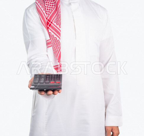 بورتريه لرجل عربي خليجي يحمل بيده الة حاسبة، العمل في ادارة الحسابات، استخدام الالة الحاسبة في اجراء العمليات الحسابية