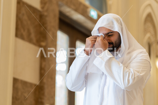 التوبة و الرجوع لله، الشعور بالخشوع والطمأنينة, رجل اماراتي عربي خليجي يرتدي الكندورة والغترة البيضاء يقف داخل احدى المساجد في الامارات العربية المتحدة، تعابيرالبكاء و الخشوع و التضرع لله