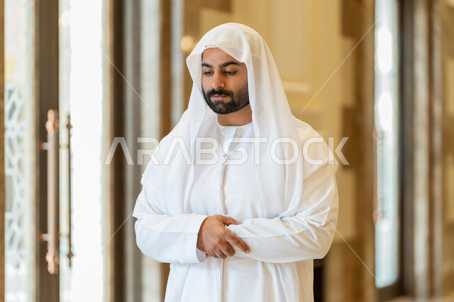 الركن الثاني من اركان الاسلام، التقرب إلى الله عن طريق القيام بالفرائض والعبادات، رجل عربي خليجي اماراتي يرتدي الكندورة والغترة البيضاء يقوم بأداء فريضة الصلاة على وقتها في المسجد، اداء الصلاوات في المساجد