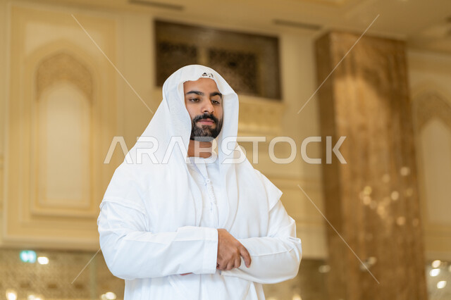 التقرب إلى الله عن طريق القيام بالفرائض والعبادات، الركن الثاني من اركان الاسلام، رجل عربي خليجي اماراتي يرتدي الكندورة والغترة البيضاء يقوم بأداء فريضة الصلاة على وقتها في المسجد، اداء الصلاوات في المساجد