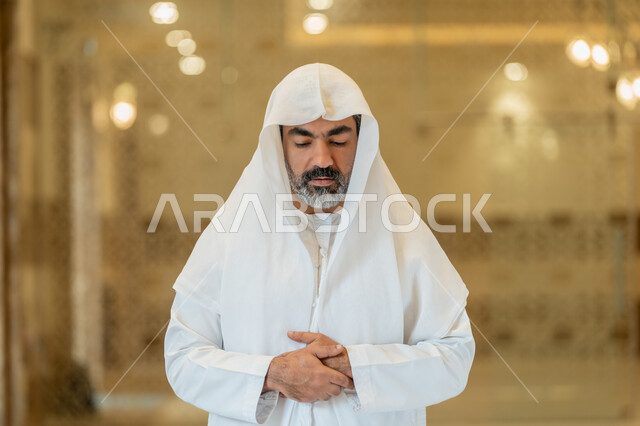 أداء الفرائض الدينية الإسلامية، إقامة الصلاة على وقتها, العبادة والتقرب إلى الله، الركن الثاني من أركان الإسلام، صورة مقربة لرجل عربي خليجي إماراتي يرتدي الكندورة والغترة البيضاء يقف باستقامة, الشعور بالخشوع والطمأنينة