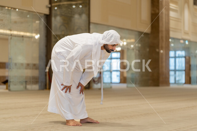 الركن الثاني من أركان الإسلام، إقامة الصلاة على وقتها, أداء الفرائض الدينية الإسلامية، العبادة والتقرب إلى الله، صورة مقربة لرجل عربي خليجي إماراتي يرتدي الكندورة والغترة البيضاء يقوم بالركوع, الشعور بالخشوع والطمأنينة