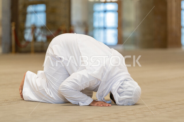 A feeling of humility and tranquility, the second pillar of Islam, performing prayers on time, performing Islamic religious duties, worship and getting closer to God, a close-up picture of an Arab Gulf-Emirati man wearing a kandura and a white ghutra, prostrating in one of the mosques