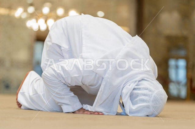 الشعور بالخشوع والطمأنينة, الركن الثاني من أركان الإسلام، إقامة الصلاة على وقتها, أداء الفرائض الدينية الإسلامية، العبادة والتقرب إلى الله، صورة لرجل عربي خليجي إماراتي يرتدي الكندورة والغترة البيضاء يقوم بالسجود في احد المساجد