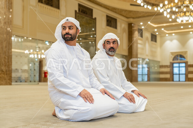 مفهوم أركان الإسلام, إقامة الصلاة على وقتها، أداء الفرائض الدينية الإسلامية، رجلان عرب خليجيان إماراتيان يرتدون الكندورة والغترة البيضاء يجلسون في المسجد يقوم بالتسليم في ختام صلاته، الشعور بالخشوع والطمأنينة، العبادة والتقرب إلى الله