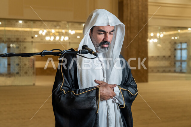أداء فرائض الدين الإسلامي, إقامة الصلاة على وقتها، إمامة المسلمين في المسجد, الشعور بالخشوع والطمأنينة, الركن الثاني من أركان الإسلام, صورة مقربة لإمام عربي خليجي إماراتي يرتدي البشت والكندورة والغترة البيضاء يقوم بأداء فريضة الصلاة