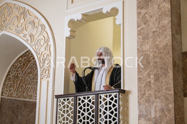 مفهوم العبادة والتقرب إلى الله تعالى, توجيه الناس نحو الحق والهداية, دور أئمة المساجد والخطباء في نشر الدين، إمام عربي خليجي إماراتي يرتدي البشت والكندورة والغترة البيضاء يقف أمام مكبر الصوت ويلقي الخطبة على المنبر, نداء المسلمين لأداء الفرائض