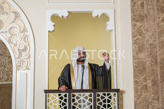 توجيه الناس نحو الحق والهداية, مفهوم العبادة والتقرب إلى الله تعالى, دور أئمة المساجد والخطباء في نشر الدين، إمام عربي خليجي إماراتي يرتدي البشت والكندورة والغترة البيضاء يقف أمام مكبر الصوت ويلقي الخطبة على المنبر, نداء المسلمين لأداء الفرائض