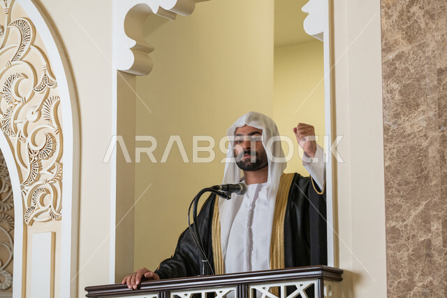 مفهوم العبادة والتقرب إلى الله تعالى, توجيه الناس نحو الحق والهداية, دور أئمة المساجد والخطباء في نشر الدين، إمام عربي خليجي إماراتي يرتدي البشت والكندورة والغترة البيضاء يقف أمام مكبر الصوت ويلقي الخطبة على المنبر, نداء المسلمين لأداء الفرائض