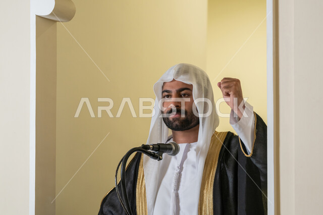توجيه الناس نحو الحق والهداية, مفهوم العبادة والتقرب إلى الله تعالى, دور أئمة المساجد والخطباء في نشر الدين، إمام عربي خليجي إماراتي يرتدي البشت والكندورة والغترة البيضاء يقف أمام مكبر الصوت ويلقي الخطبة على المنبر, نداء المسلمين لأداء الفرائض