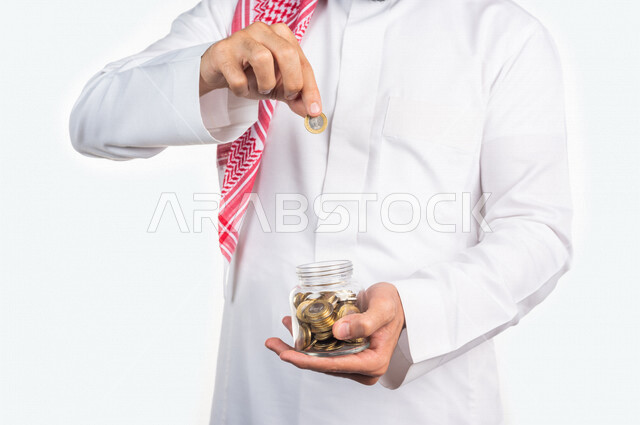 بورتريه لرجل عربي خليجي، إدخار وتوفير الاموال في وعاء زجاجي، النمو والأرباح المالية، إدخار وتوفير الاموال، العملات المعدنية