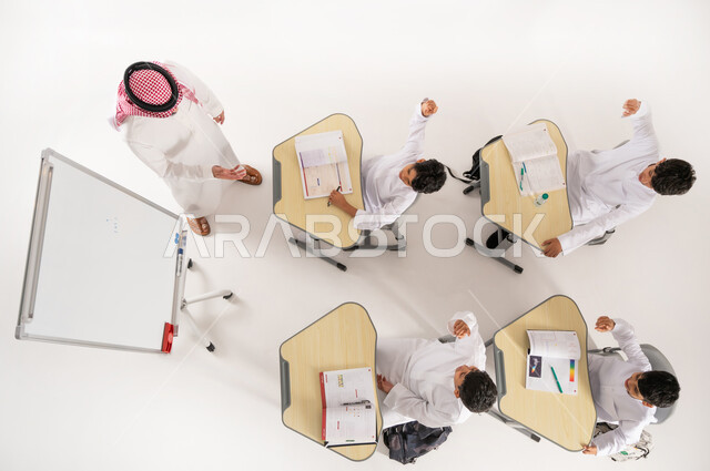 Concept of diligence and striving for excellence, developing creative skills, Saudi Arabian Gulf students wearing traditional dress raising their hands to participate, doing homework, vertical top portrait of Saudi Arabian Gulf teacher helping students with group activities, white background